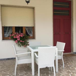 una mesa blanca y sillas con puerta roja en La Perla del Mare en Martinsicuro