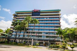 een hoog gebouw met palmbomen ervoor bij Kapok Hotel in Port-of-Spain