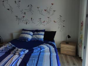 a bedroom with a bed with blue sheets and birds on the wall at Apartment Mikuš in Stinica