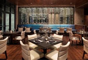 a restaurant with tables and chairs and a wall of wine bottles at Zota Beach Resort in Longboat Key