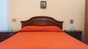 クストナーチにあるBed and Breakfast Arcobalenoのベッド1台(オレンジ色のベッドカバー、ナイトスタンド2台付)