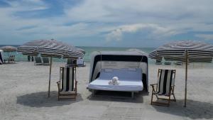 a bed and two chairs on a beach with umbrellas at Zota Beach Resort in Longboat Key