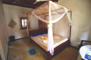 a bedroom with a canopy bed with curtains on it at Wine Tree Garden Guesthouse in Mirissa
