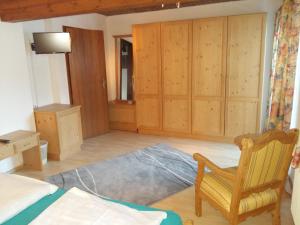 1 dormitorio con 1 cama, 1 silla y armarios de madera en Haus Kropf, en Mittersill