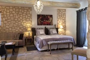 ein Schlafzimmer mit einem Bett, einer Couch und einem Kronleuchter in der Unterkunft Château de la Merletade in Cheval-Blanc