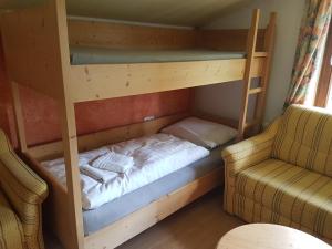 łóżko piętrowe w pokoju z kanapą i krzesłem w obiekcie Haus Kropf w mieście Mittersill