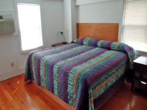 a bedroom with a bed with a colorful blanket on it at Adirondack Inn in Saratoga Springs