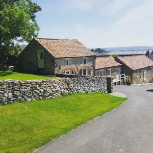 a stone house with a stone wall and a road at Prospect Farm Cottages in Allerston