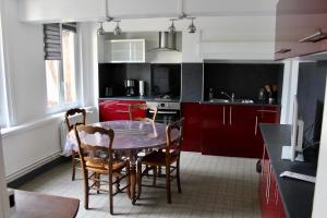 a kitchen with red cabinets and a table and chairs at LES OISEAUX (L'HIRONDELLE) in Rouen