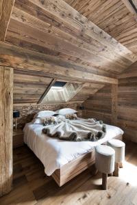 Cama grande en habitación con techo de madera en Les Rhodos en La Clusaz