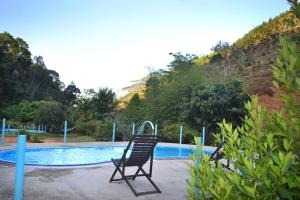 a chair sitting in front of a swimming pool at Pousada Recanto da Mata in Marechal Floriano