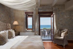 Porto Vitilo Boutique Hotel في كارافوستشين: غرفة نوم مع سرير وإطلالة على المحيط