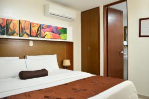 1 dormitorio con 1 cama blanca grande y una pintura en la pared en Hotel Tarigua Ocaña, en Ocaña