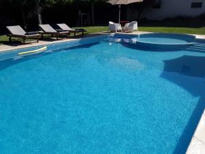a large blue swimming pool with chairs and an umbrella at Casa Castedo do Douro in Castedo