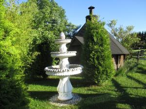 a white fountain in the grass with a house in the background at Behrs Hof in Scharmbeck