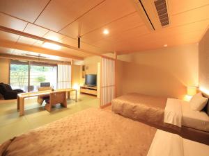 1 dormitorio con 1 cama y escritorio con TV en Shimoda Central Hotel, en Shimoda