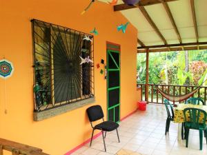 Habitación con pared de color naranja, mesa y sillas. en Cabinas Caribe Luna en Cahuita