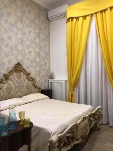 ナポリにあるRoyal Gismondaのベッドルーム1室(黄色いカーテンとテーブル付きのベッド1台付)