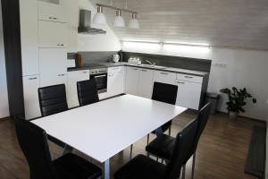 a white kitchen with a white table and chairs at Lake House Apartment in Medvode