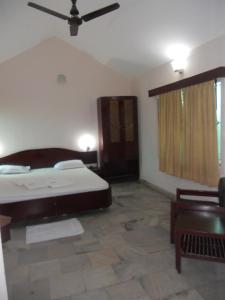 een slaapkamer met een bed en een plafondventilator bij Hotel Sadhabishegam in Vaithīsvarankoil