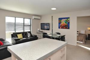 eine Küche und ein Wohnzimmer mit einem Sofa und einem Tisch in der Unterkunft Carlton Villa 3 - Christchurch Holiday Homes in Christchurch