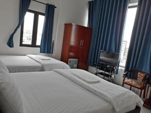 a bedroom with two beds and a television and blue curtains at Nice Hotel in Da Nang