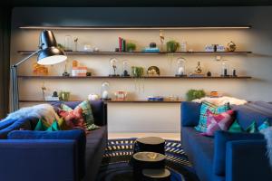 a living room with two blue couches and shelves at Naumi Auckland Airport Hotel in Auckland