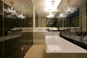 Ischia Hotel في يونغين: حمام مع حوض ومرآة كبيرة