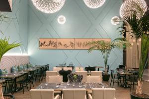 a dining room with tables and chairs and plants at Naumi Auckland Airport Hotel in Auckland