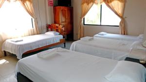 a room with three beds and a window at Casa Los Delfines in Puerto Villamil