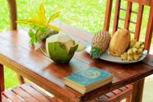 una mesa de madera con un plato de fruta y un libro en Natural Cabanas, en Tangalle