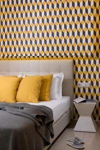 a bedroom with a bed with yellow pillows and a patterned wall at Muses Studios in Potos