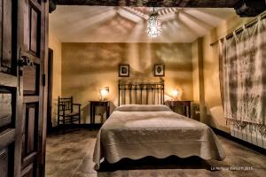Un dormitorio con una cama y dos mesas y una lámpara de araña. en La Antigua Botica, en Pasarón