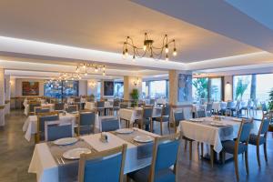 a restaurant with white tables and chairs and a chandelier at Floria Beach Hotel in Alanya