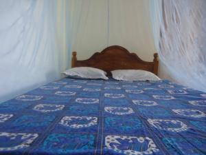 a bedroom with a bed with a blue and white quilt at Malika Homestay in Midigama