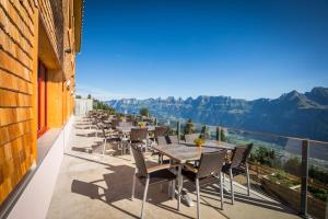 a row of tables and chairs on a balcony with mountains at Berghotel Schonhalden in Flums
