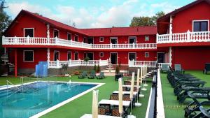 a red building with a swimming pool in front of it at Artemis Resort Wellness Hotel in Štúrovo