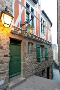 a building with green doors and a sign on it at Auberge Saint Pierre in Le Mont Saint Michel