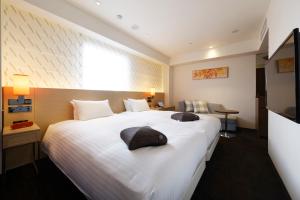 a hotel room with a large white bed with two pillows at HOTEL FORZA HAKATA-GUCHI in Fukuoka