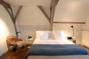 a bedroom with a large bed and a chair at Hotel Julien in Antwerp