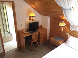 a bedroom with a bed and a desk with a television at Alte Rose Gasthaus in Ebelsbach