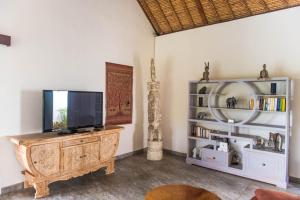 een woonkamer met een tv op een houten entertainmentcentrum bij Villa Michiko in Uluwatu