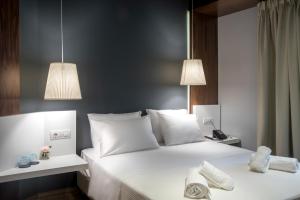 a bedroom with a bed with white sheets and pillows at AD Athens Luxury Rooms & Suites in Athens