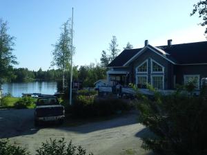 uma casa com um carro estacionado em frente a um lago em Paratiisi Villat em Gäddnäs