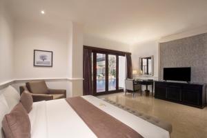 a hotel room with a large bed and a television at Grand Palace Hotel Sanur - Bali in Sanur
