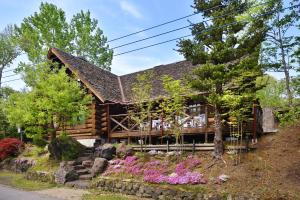 a log cabin with flowers in front of it at Rental Log Urube Village in Tsumagoi