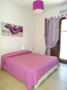 sypialnia z różowym łóżkiem i fioletowym kocem w obiekcie B&B Soleluna w mieście Veglie