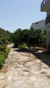 a stone walkway with a bench and trees and a building at Alekos Rooms and Apartments in Kokkari