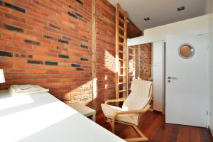 グリヴィツェにあるThe Loftのベッドと椅子が備わる客室で、レンガの壁が特徴です。