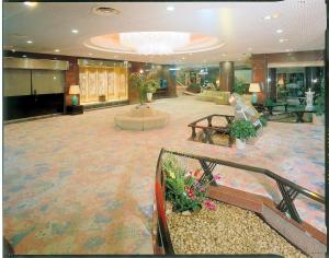 eine Lobby eines Hotels mit Tischen und Blumen in der Unterkunft Yunogo Grand Hotel in Mimasaka